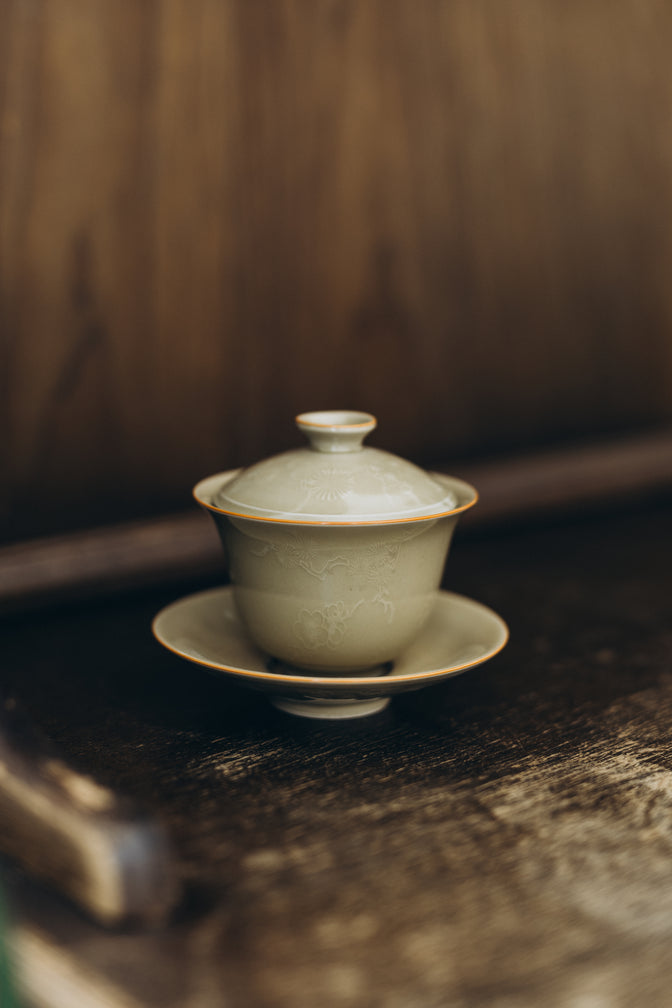 Curls ceramic gaiwan with its lid and saucer on a wooden shelf.