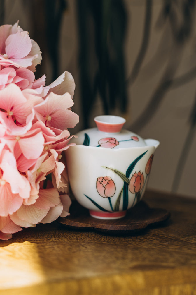 Pink Tulip gaiwan with its lid on, displayed beside pink hydrangeas.