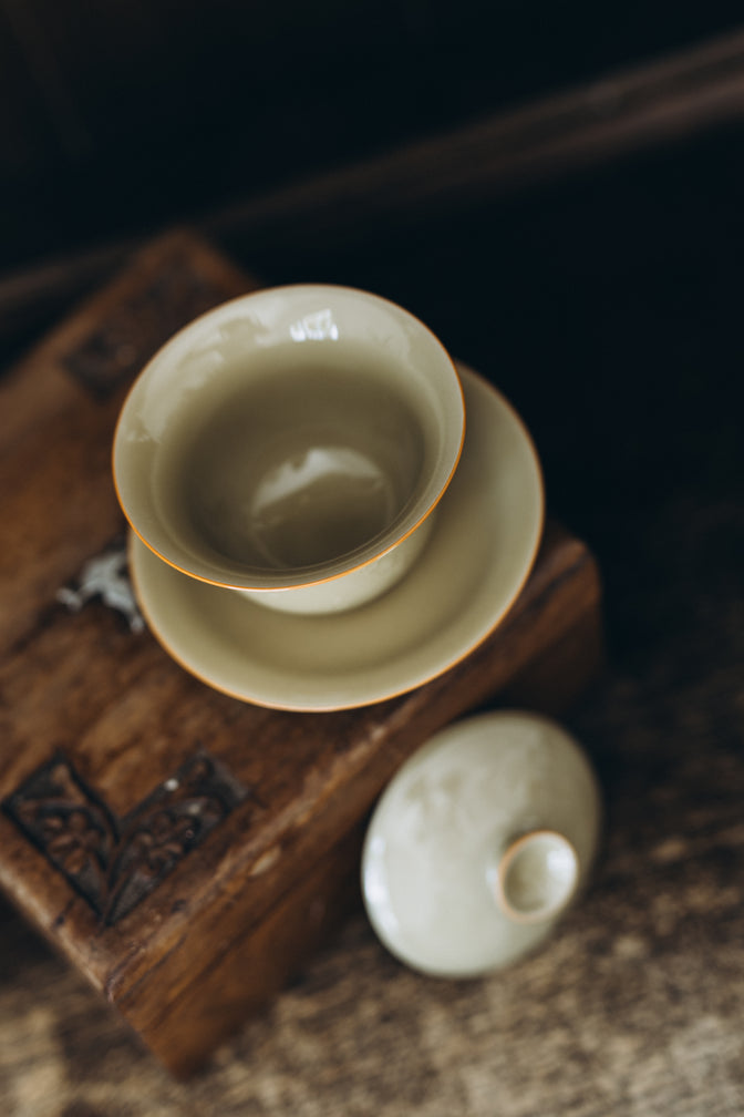 Open Curls ceramic gaiwan with its lid beside the saucer, viewed from above.