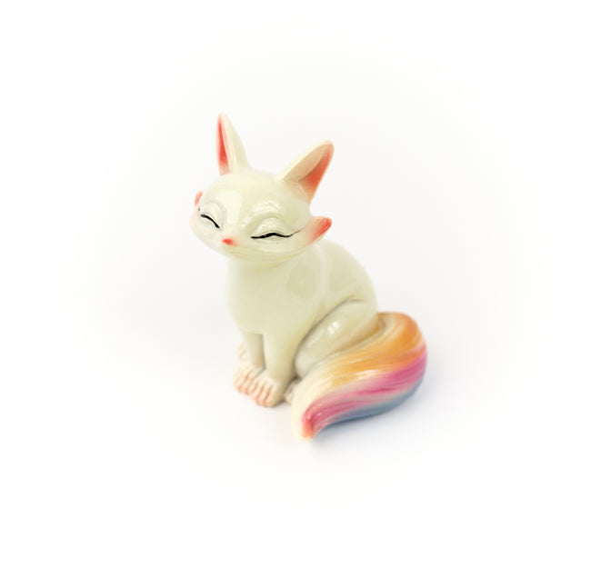 Seated Wonder Fox tea pet with closed eyes and a colorful curled tail.