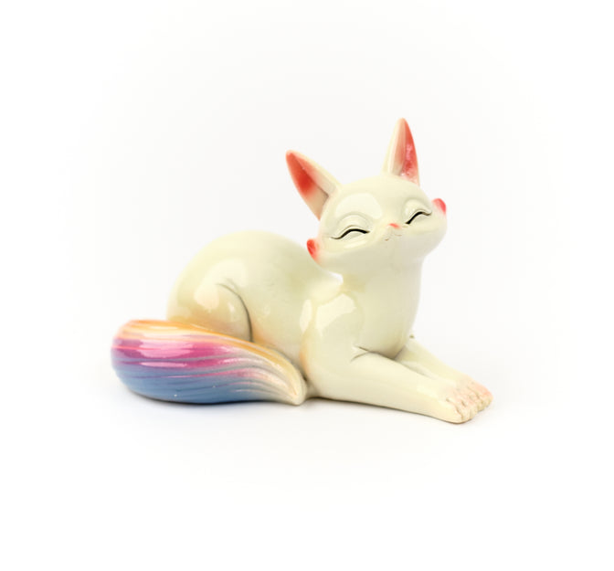 Reclining Wonder Fox tea pet with a rainbow-colored tail.