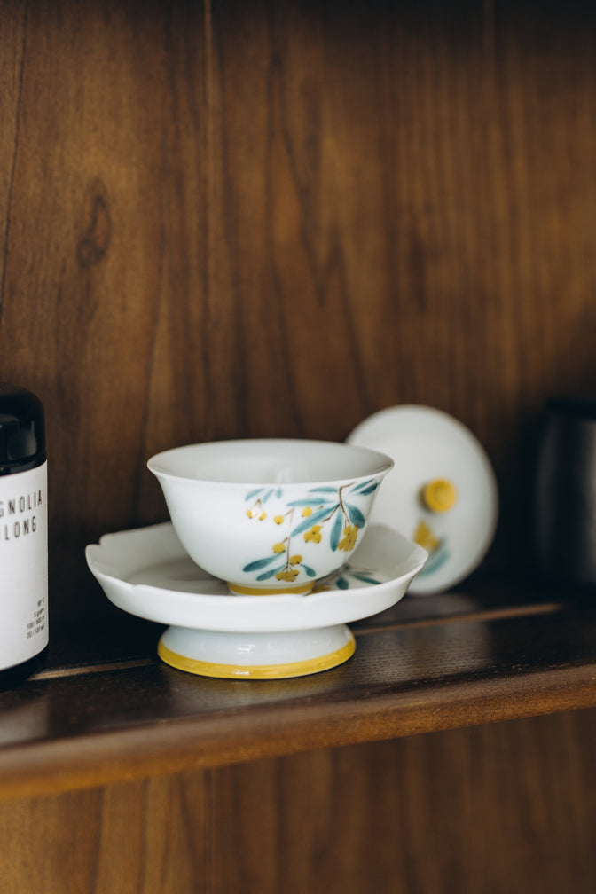 Open Japanese Plums gaiwan with its floral lid resting beside the saucer.