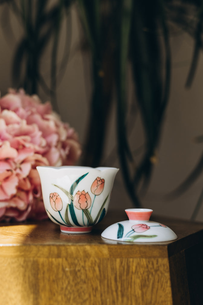 Open Pink Tulip gaiwan with its lid beside the bowl and pink hydrangeas behind.